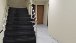 A staircase with black steps and a metal railing, leading to a door at the top. - Hotel londres (Gama)