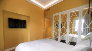 Ein Schlafzimmer mit einem großen Bett, einem flachbildfernseher an der Wand und einer weißen Trennwand mit kreisförmigen Mustern.