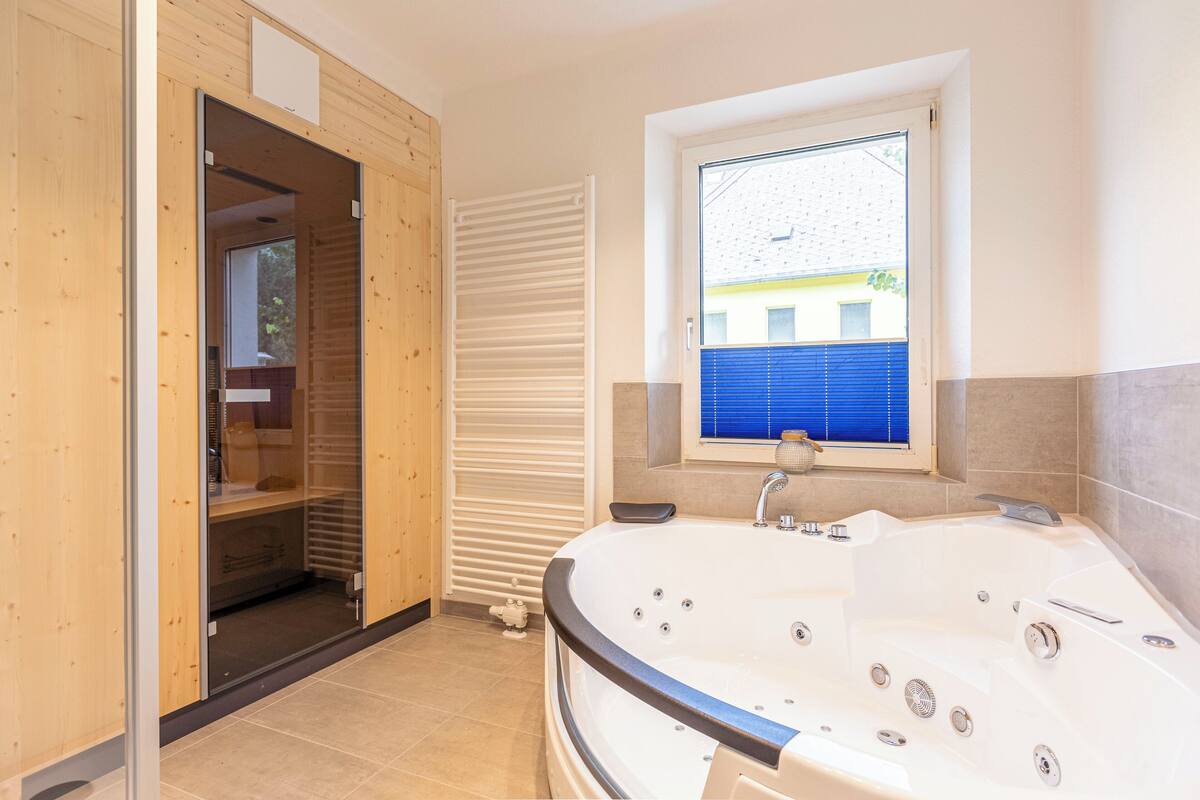 Un baño moderno con una bañera grande, cabina de ducha y una ventana con vistas al exterior.