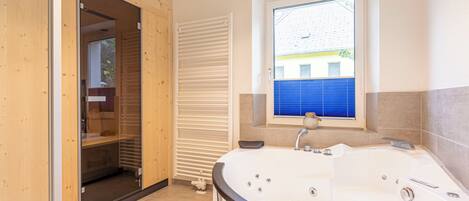 Un baño moderno con una bañera grande, cabina de ducha y una ventana con vistas al exterior.