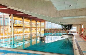 Une piscine offrant une vue dégagée sur les environs, avec notamment un espace détente comprenant des chaises et des plantes.