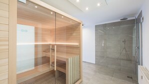 Un baño moderno con ducha de vidrio, paneles de madera y un perchero visible.