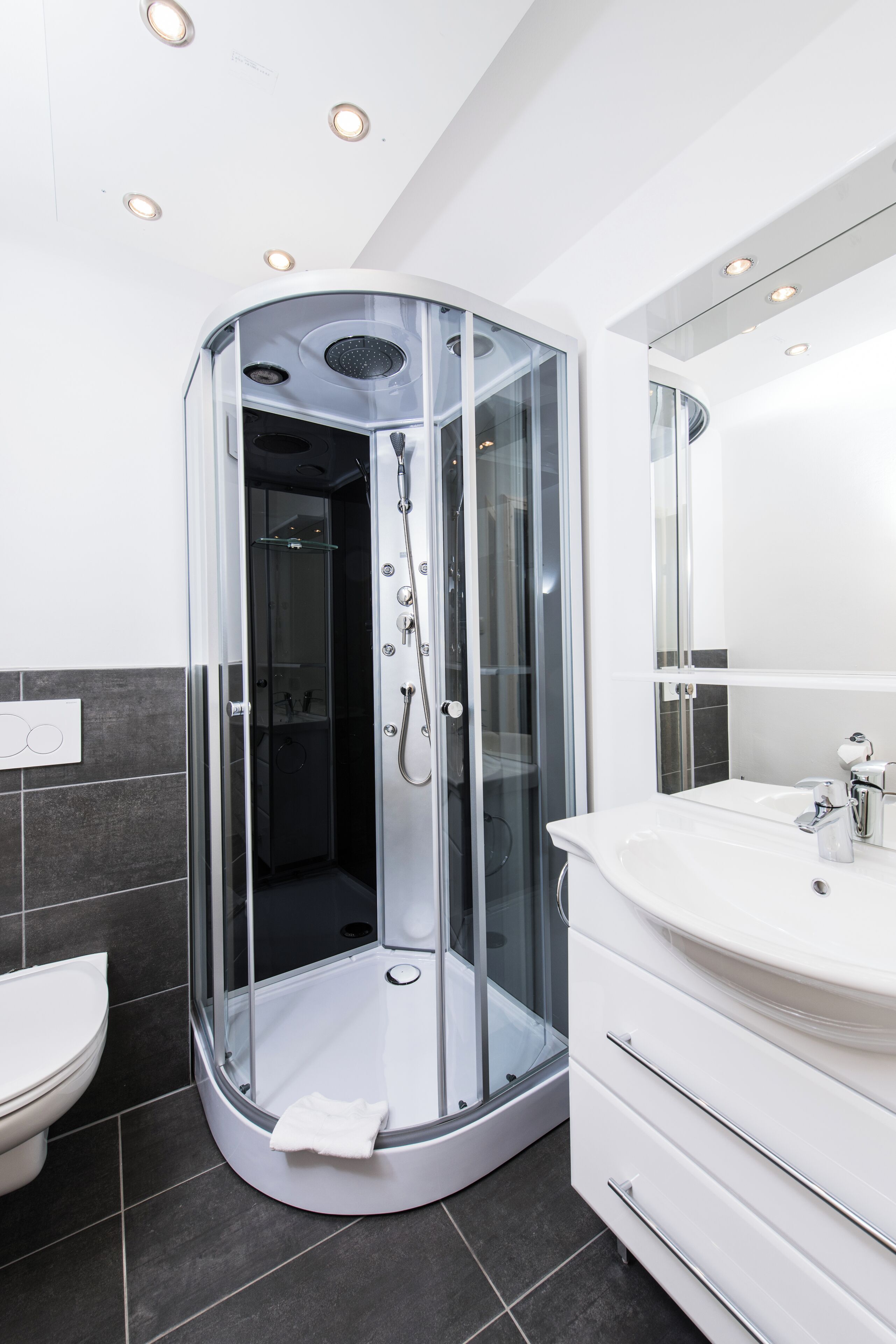 Une salle de bain moderne avec une douche à parois de verre, un lavabo blanc et un grand miroir.