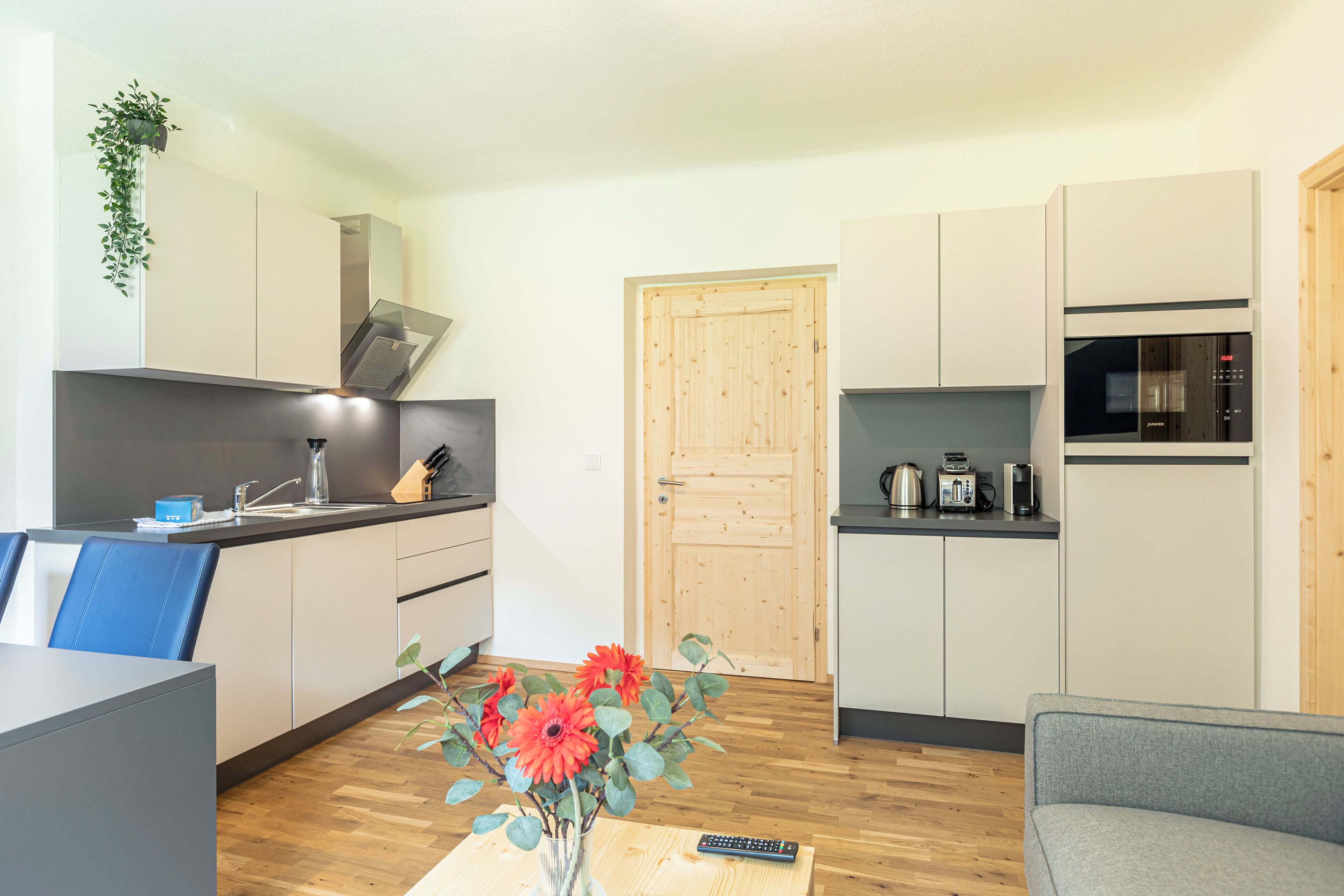 A modern kitchen with white cabinets, a wooden door, and a built-in microwave.