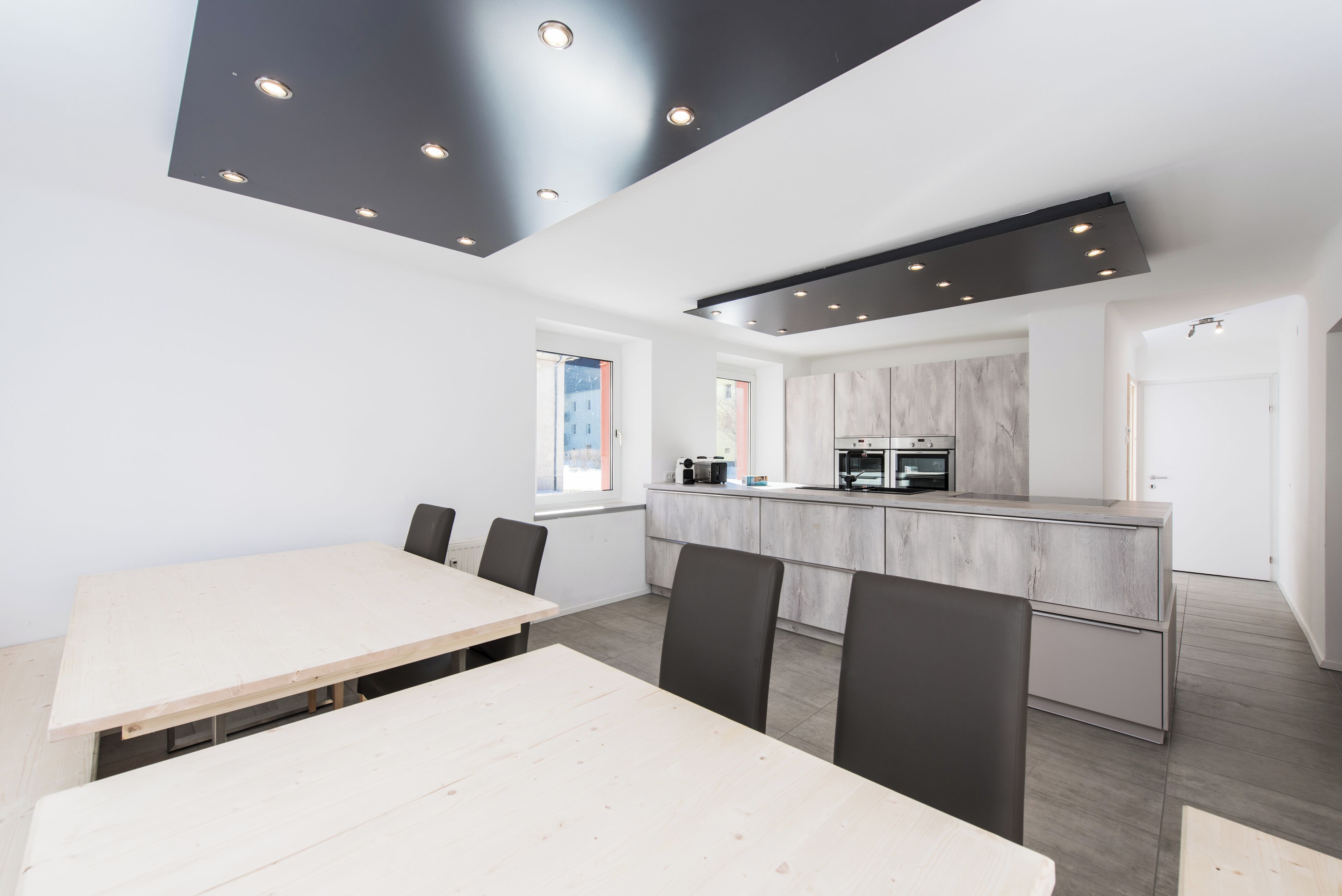 A modern kitchen with a central island, white walls, and recessed lighting.