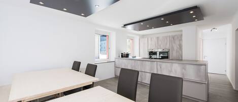 A modern kitchen with a central island, white walls, and recessed lighting.