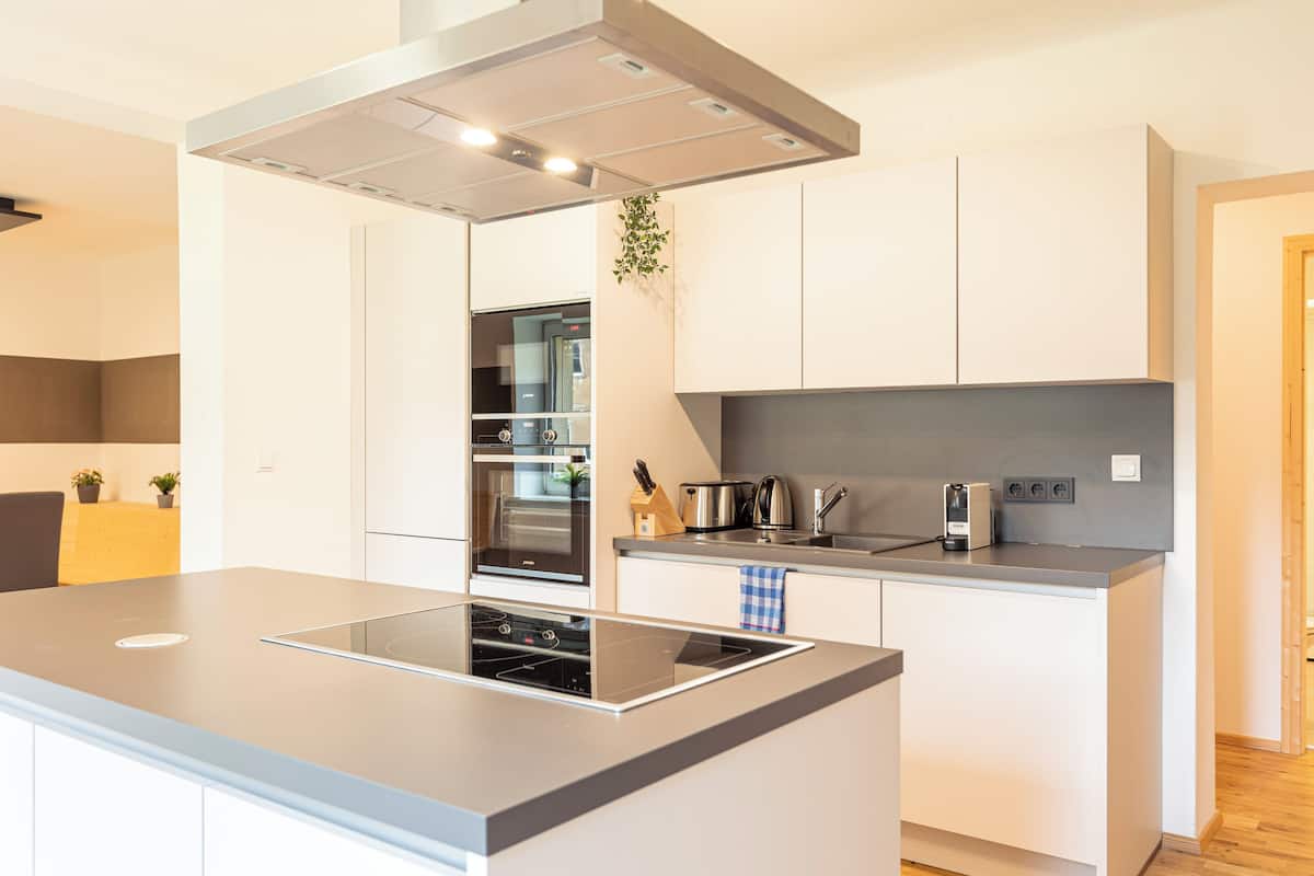 Una cocina moderna con una isla central, horno empotrado y electrodomésticos de acero inoxidable.