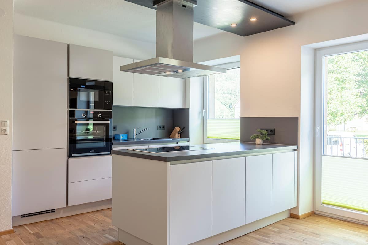 Una cocina moderna con armarios blancos, una isla central y un horno empotrado.