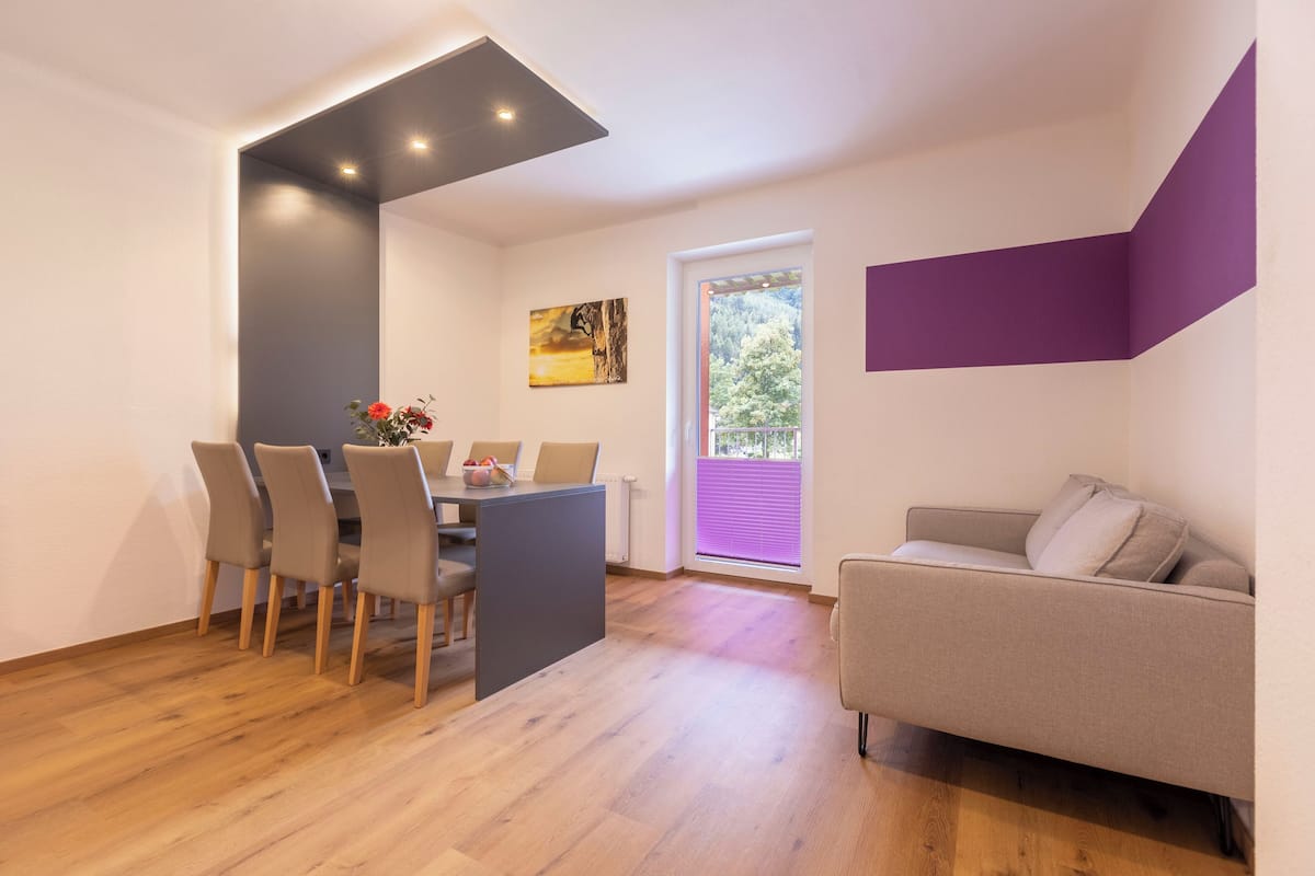 Una sala moderna con comedor, un sofá y un cuadro en la pared.