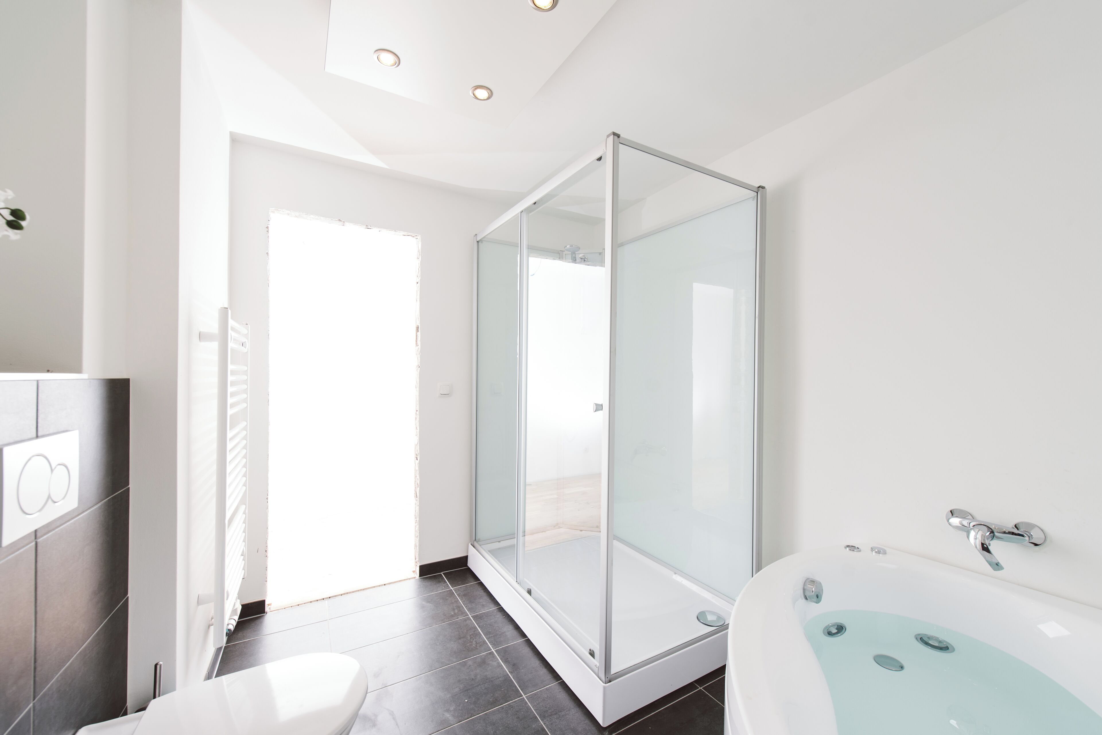 A modern bathroom with a glass shower enclosure, a freestanding bathtub, and a white sink.