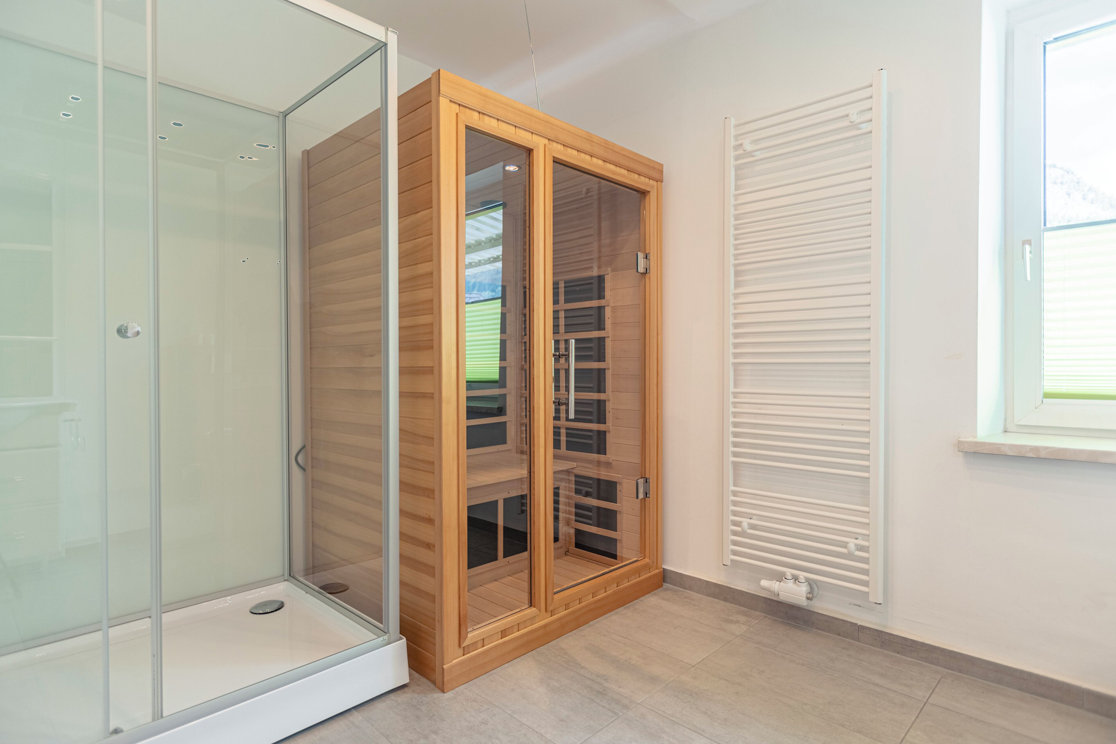 A room with a glass shower enclosure, a wooden wardrobe with glass doors, and a white radiator.