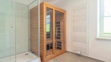 A room with a glass shower enclosure, a wooden wardrobe with glass doors, and a white radiator.