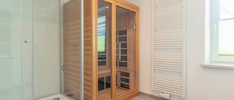 A room with a glass shower enclosure, a wooden wardrobe with glass doors, and a white radiator.