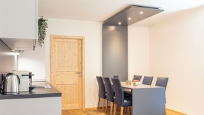 Una cocina compacta con estufa integrada, una puerta de madera y un comedor con mesa y sillas.