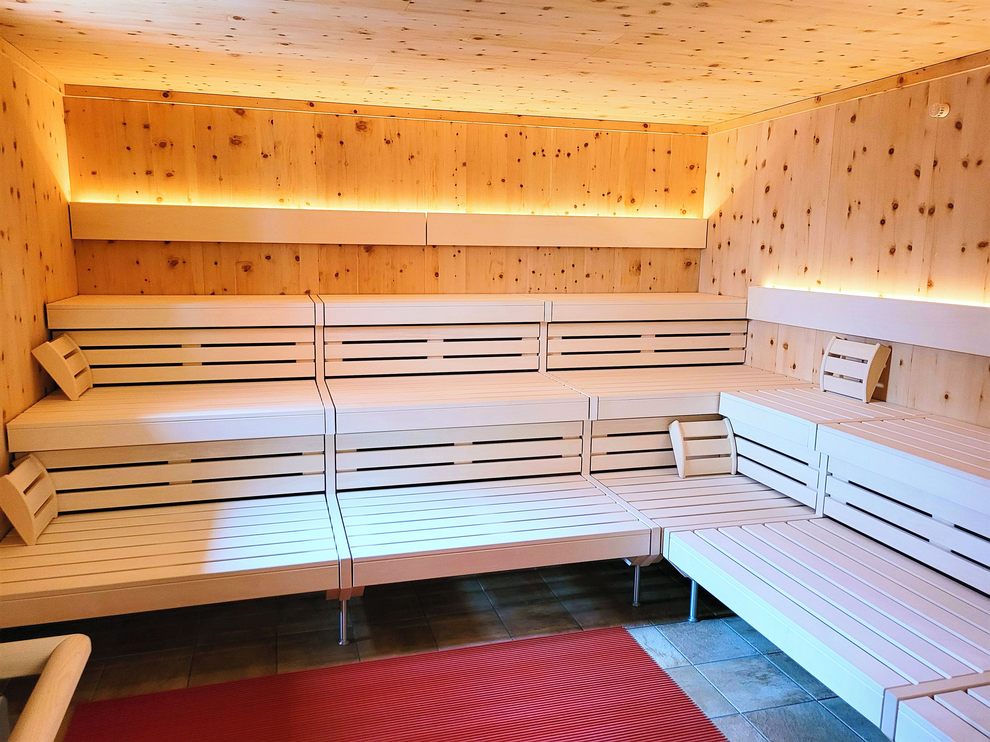 Eine Sauna mit mehreren Bänken und einer Holzbalkendecke.
