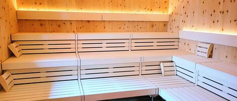 A sauna with multiple benches and a wooden ceiling.