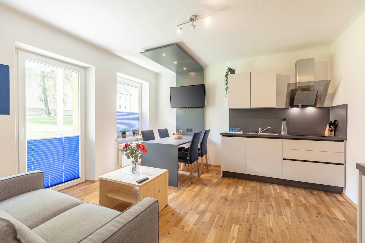 Una sala de estar moderna con un sofá, una mesa de centro y un comedor con una mesa y sillas.