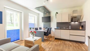 A modern living room with a sofa, a coffee table, and a dining area with a table and chairs.