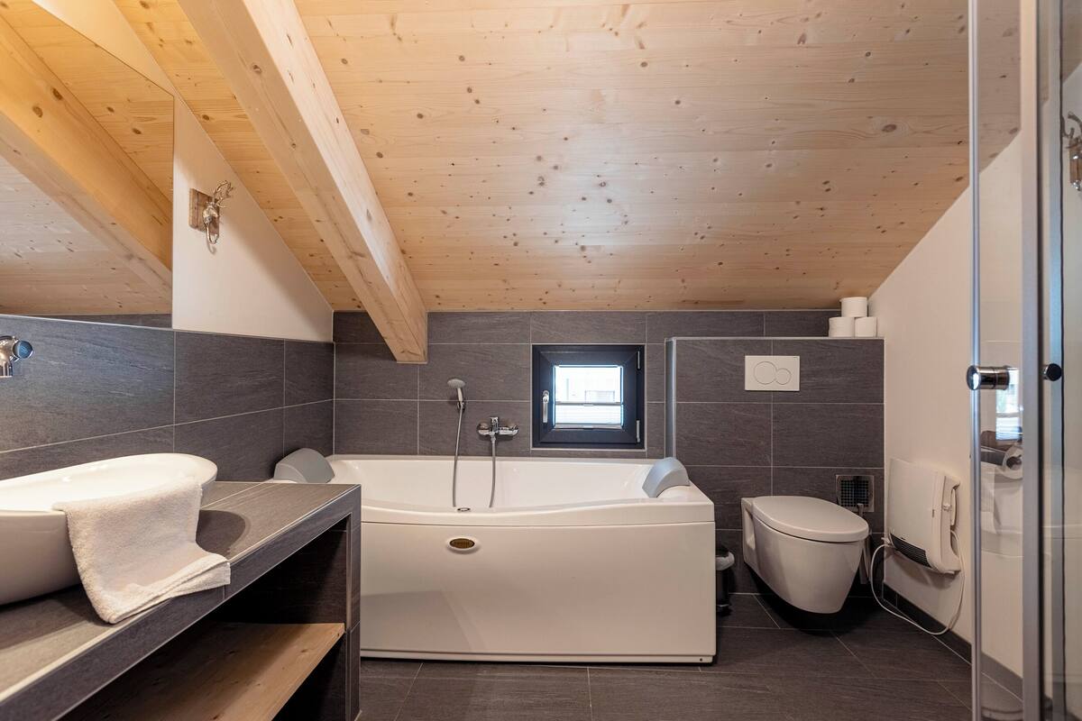 Un baño moderno con una bañera independiente, inodoro y zona de ducha.
