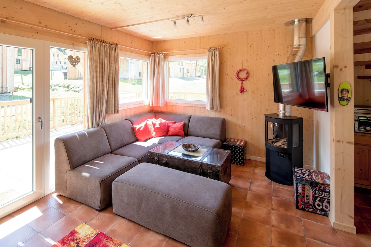 Una sala de estar acogedora con un sofá modular, una mesa de centro de vidrio y una chimenea.