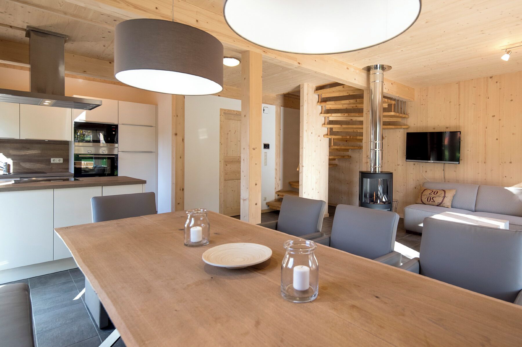 A modern kitchen with a built-in oven and a dining area with a wooden table and chairs.