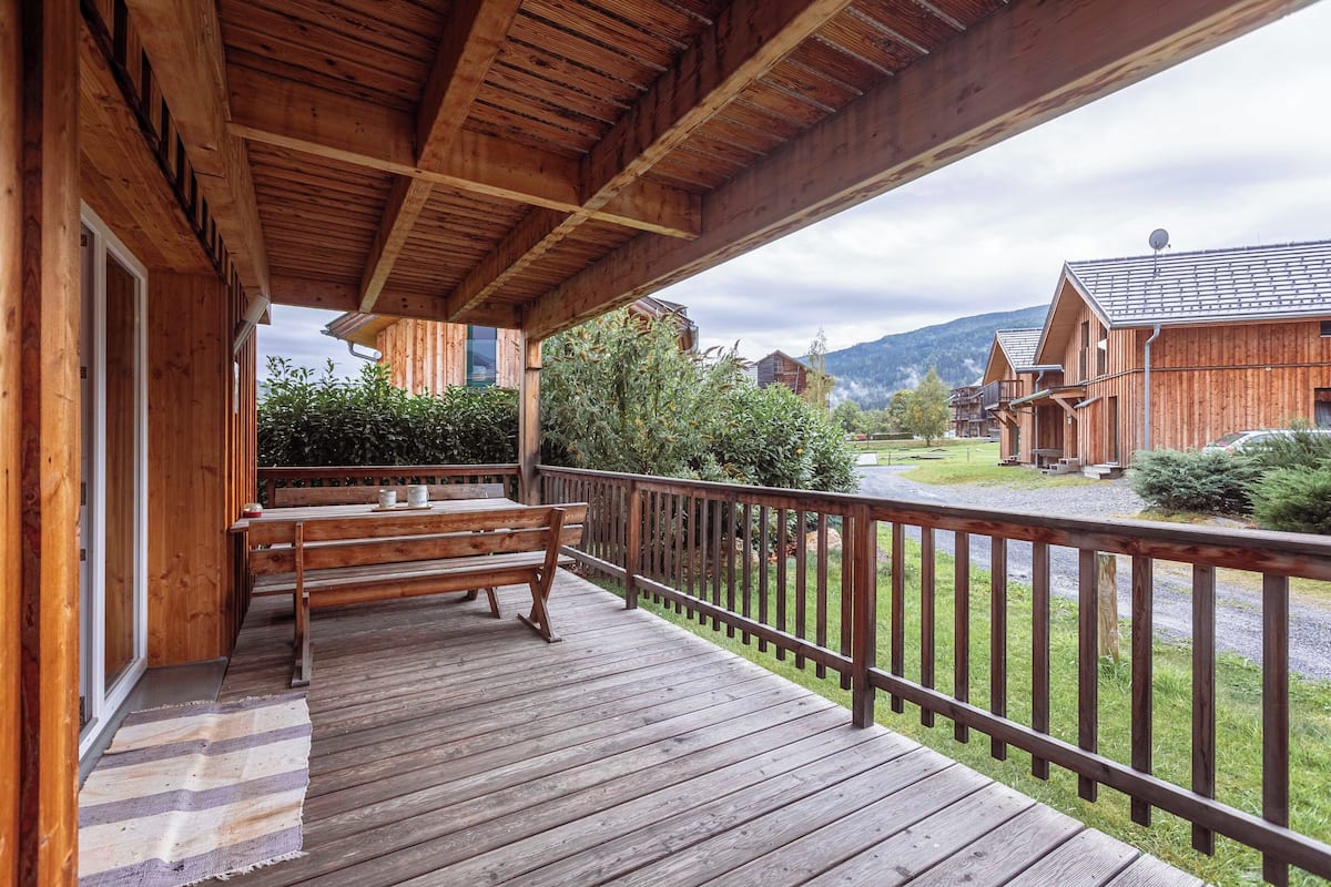 A wooden deck with a bench and a railing, overlooking a mountain landscape.