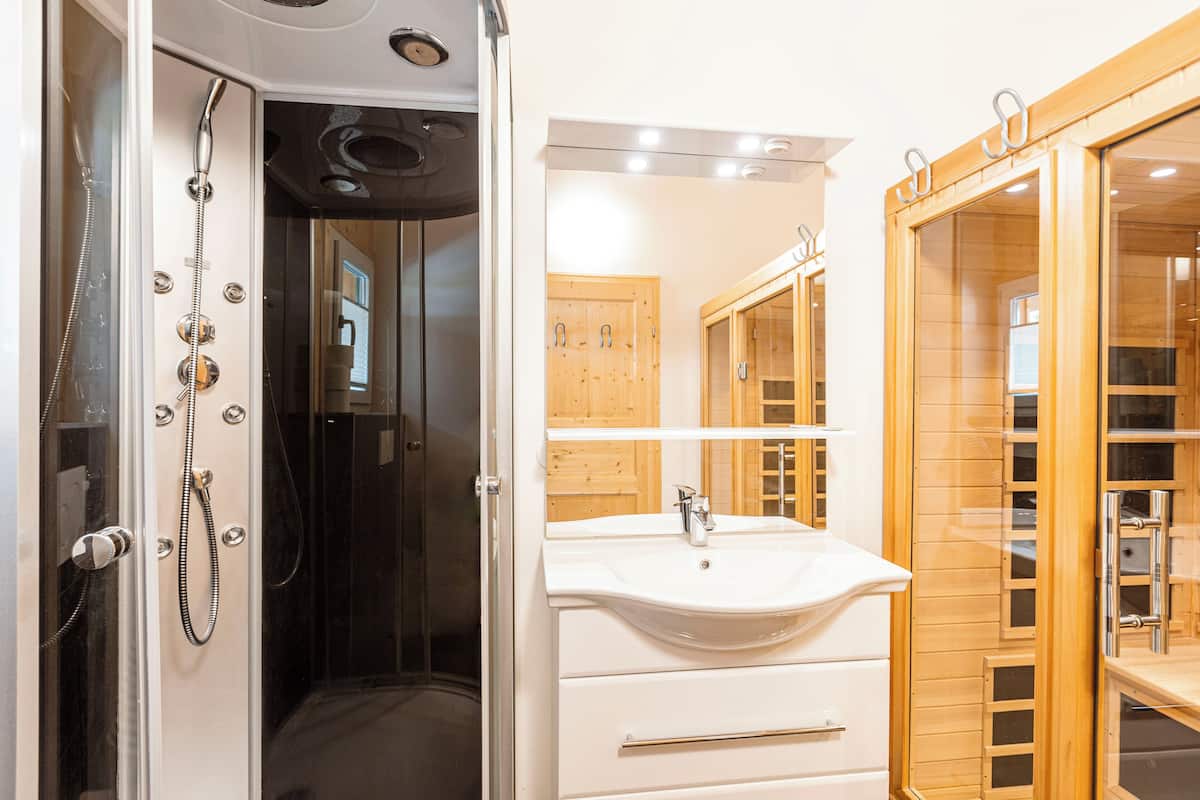 A modern bathroom with a walk-in shower, a large mirror, and wooden cabinetry.
