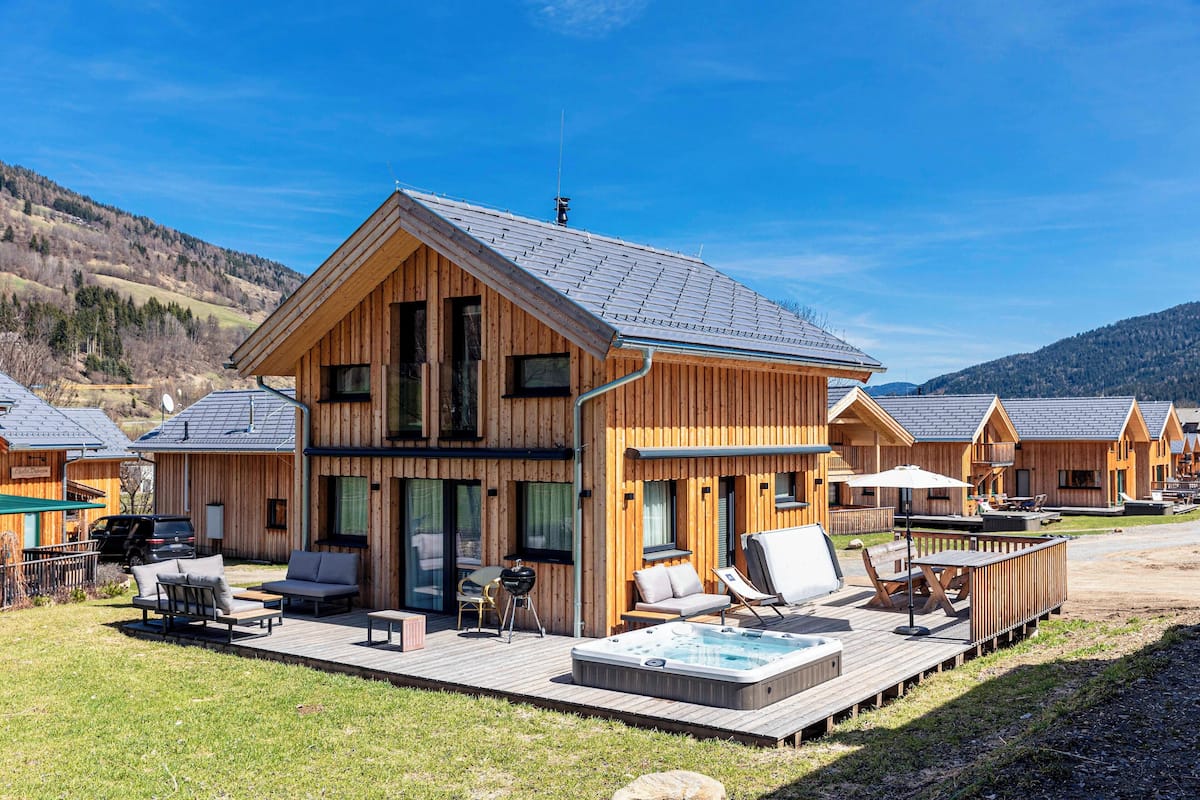 Una cabaña de madera con hidromasaje, mobiliario exterior y una terraza.