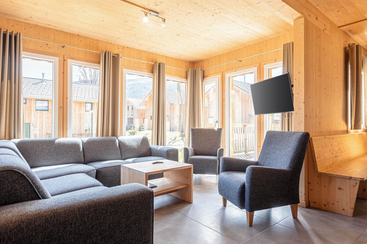 A modern living room with a sectional sofa, a small table, and a TV mounted on the wall.