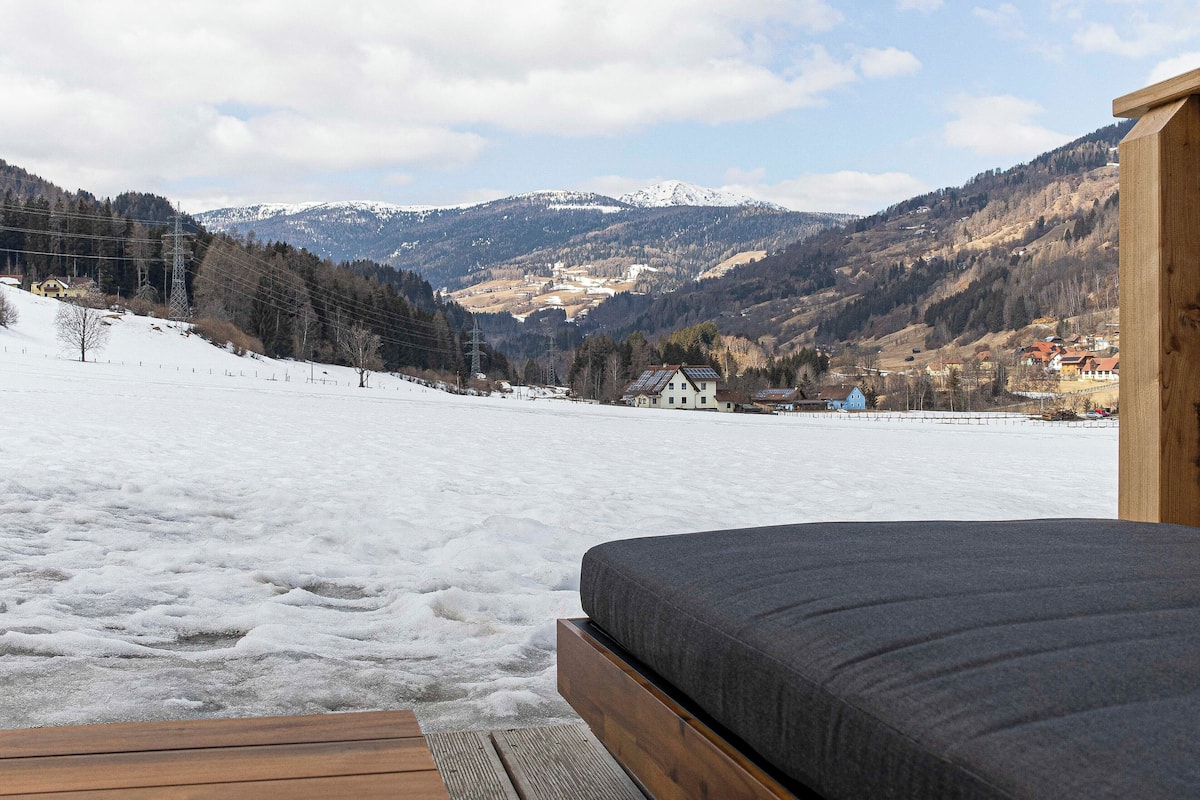 Paisaje nevado con una terraza de madera y una cama.