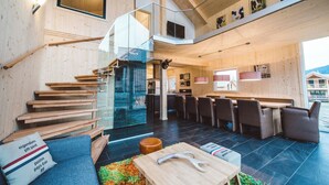 A modern interior with a staircase, seating area, and a dining space. - Kreischberg Chalets by ALPS RESORTS (Sankt Georgen am Kreischberg)