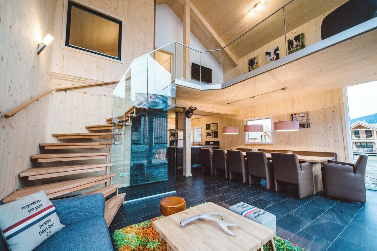 Un interior moderno con una escalera, zona de estar y comedor.