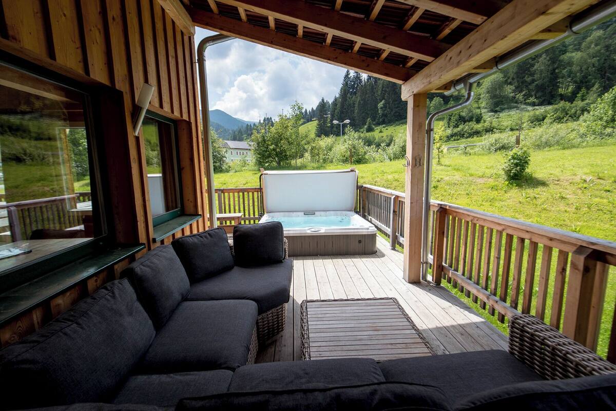 A wooden deck with a sofa and a hot tub.