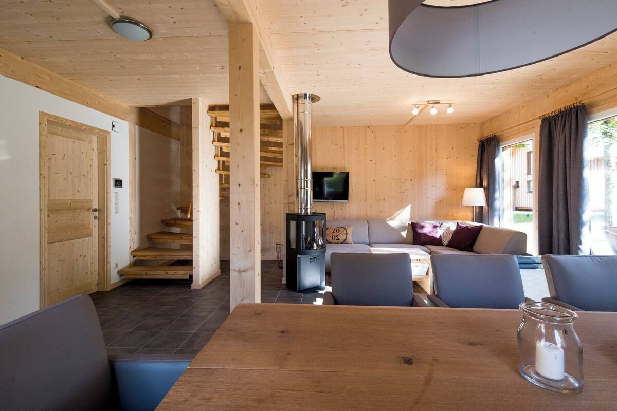 Un interior de madera con comedor, sofá y televisor.