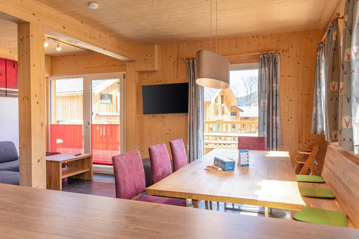 Un interior de madera con una gran mesa, sillas y un televisor.