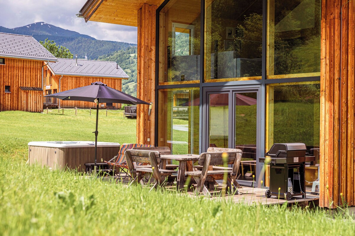 A wooden building with a patio area featuring outdoor seating and a grill.