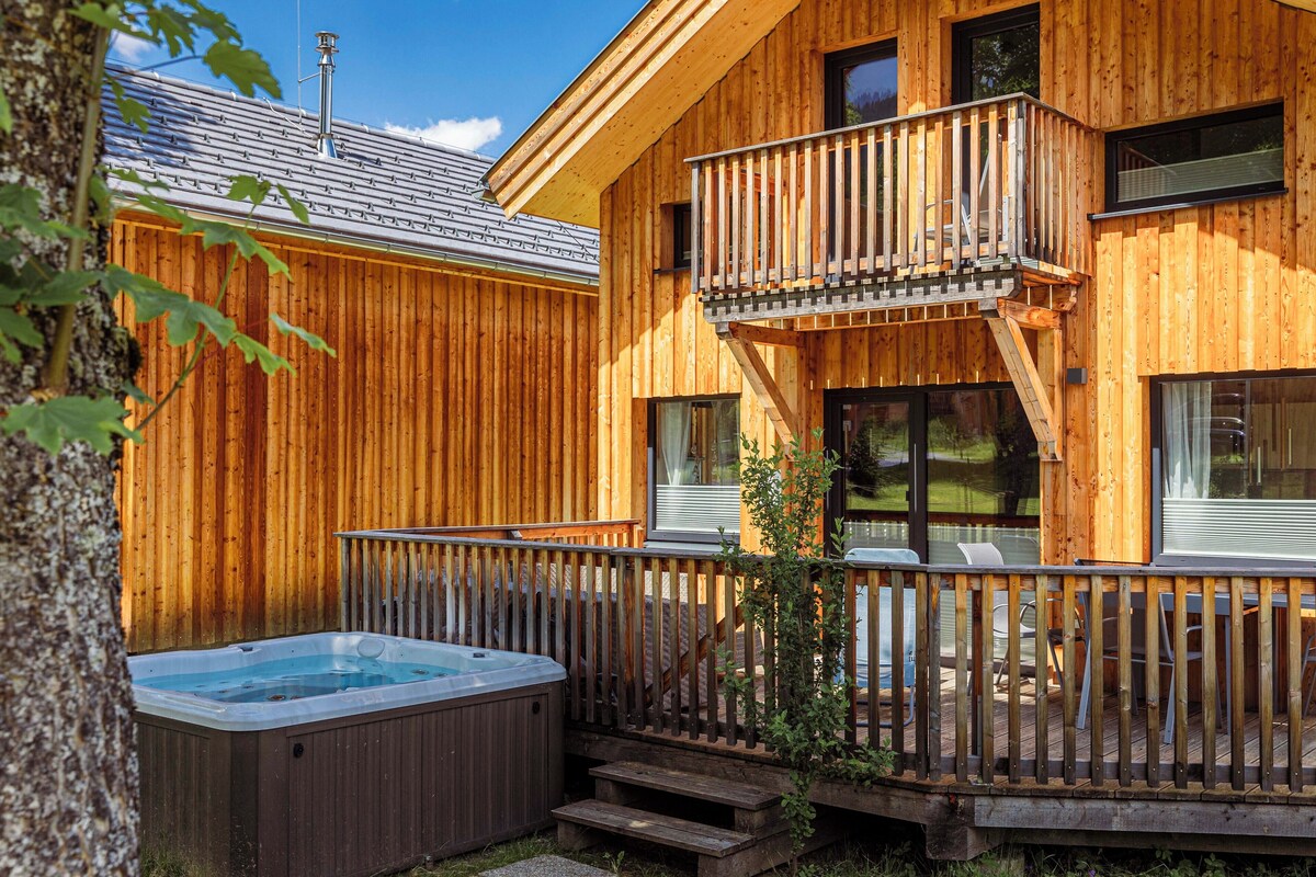 A wooden cabin with a hot tub, a balcony, and a deck.