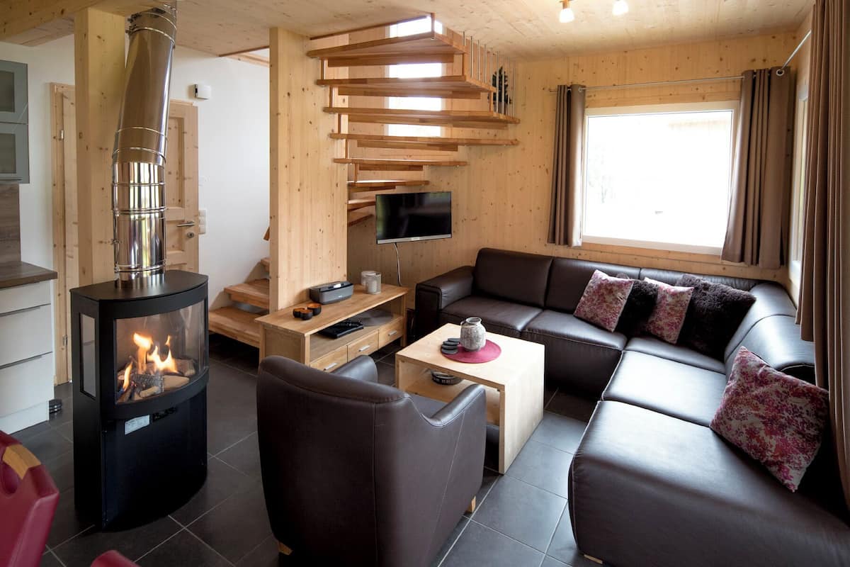 Una sala de estar moderna con una chimenea de leña, un sofá de cuero y un televisor de pantalla plana.
