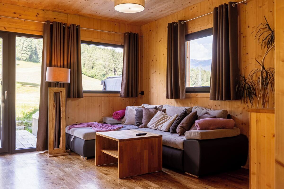 Un interior de madera con un sofá, una lámpara y cortinas.