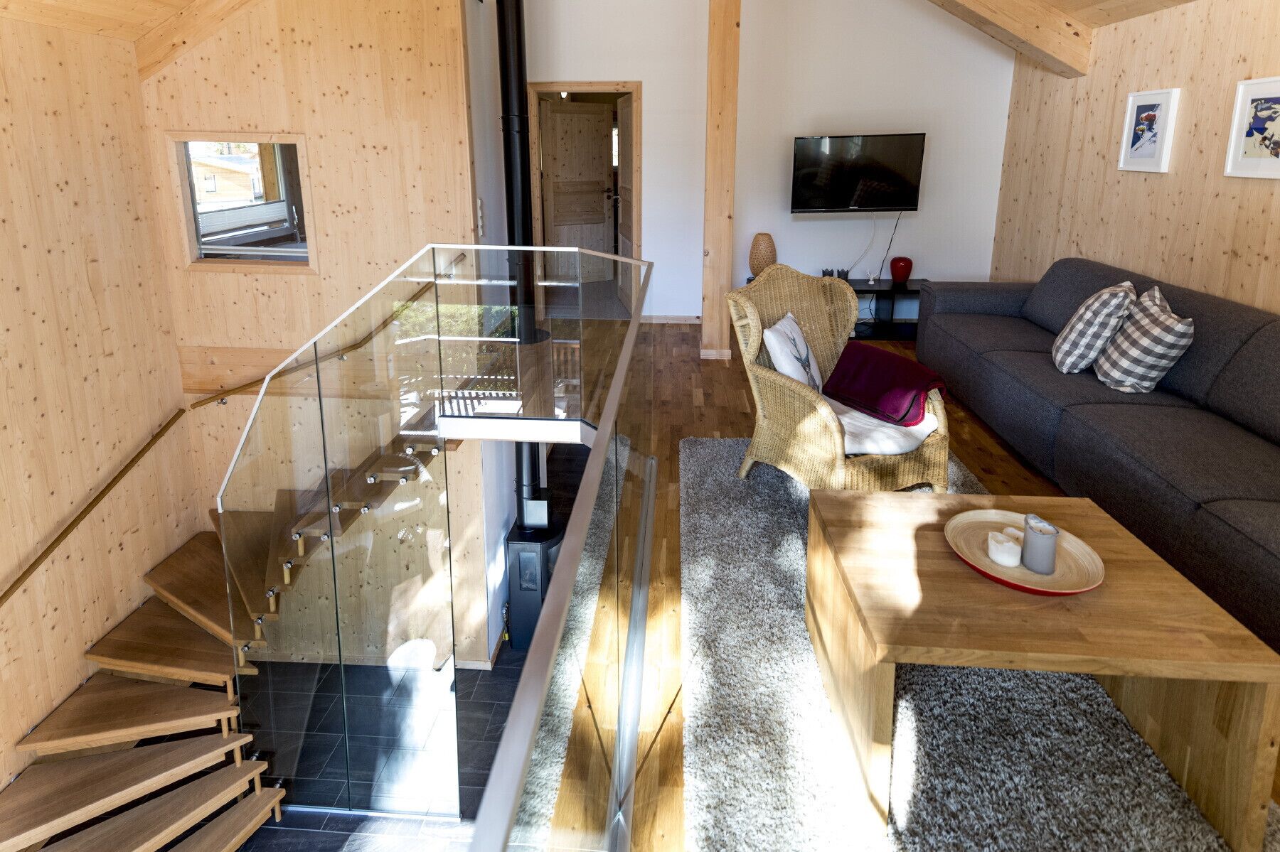 En modern inredning med en trätrappa, en soffa, en tv och en matplats.