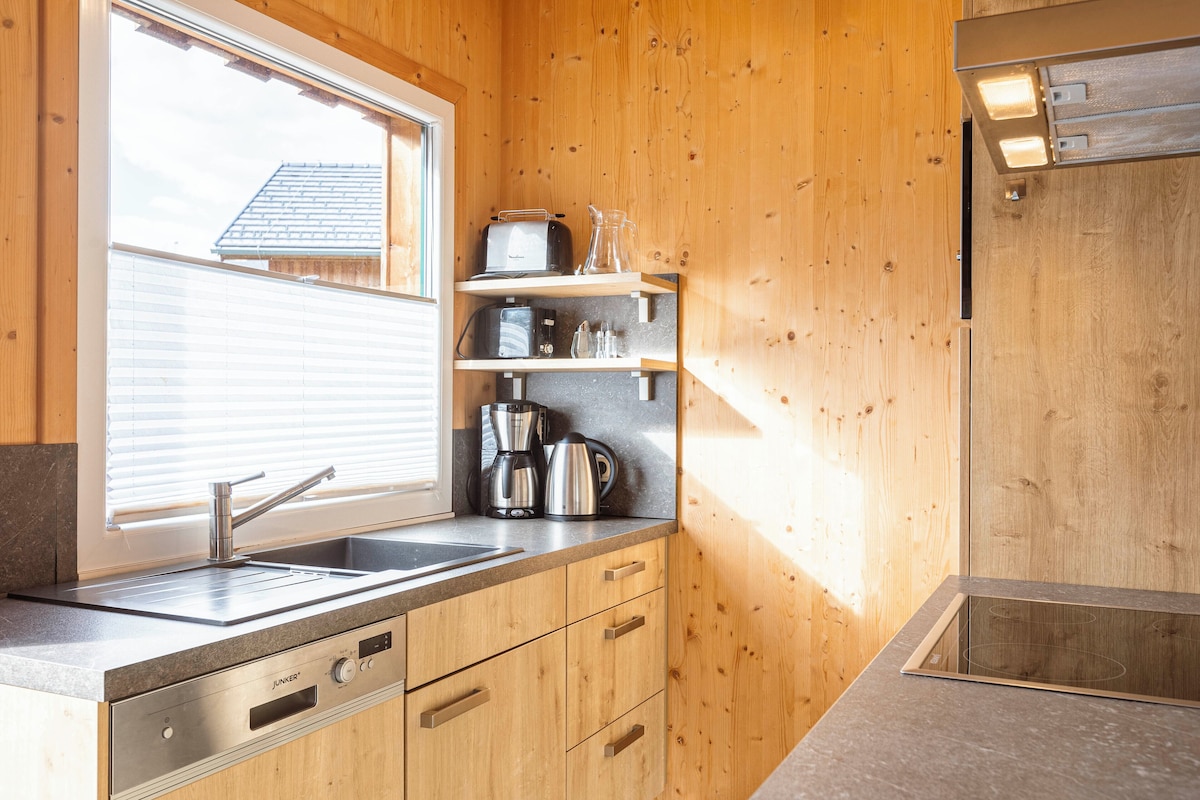 A compact kitchen with wooden cabinets, a stainless steel sink, and a built-in microwave.