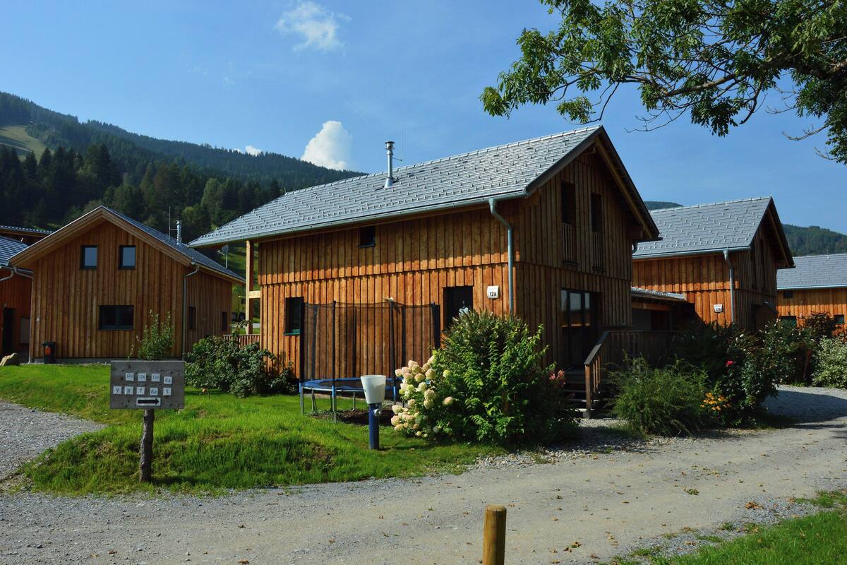 A wooden building with a sloped roof, a gravel driveway, and a signboard.