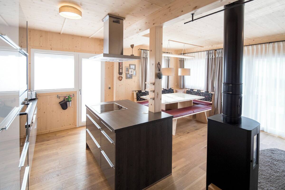 Una cocina moderna con paredes de madera, una isla central y una estufa negra.
