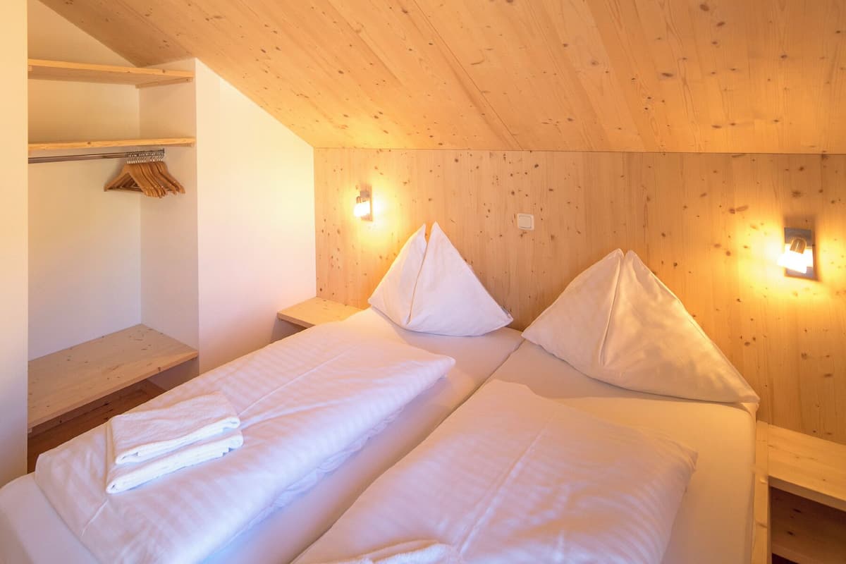 Una habitación con dos camas, paredes y techo de madera.