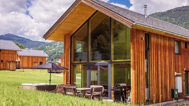 A wooden cabin with large windows, outdoor seating, and a view of the surrounding mountains. - Kreischberg Chalets by ALPS RESORTS (Sankt Georgen am Kreischberg)