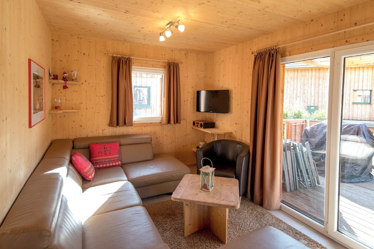 A cozy room with a sofa, a small table, a TV, and a sliding glass door to an outdoor area.