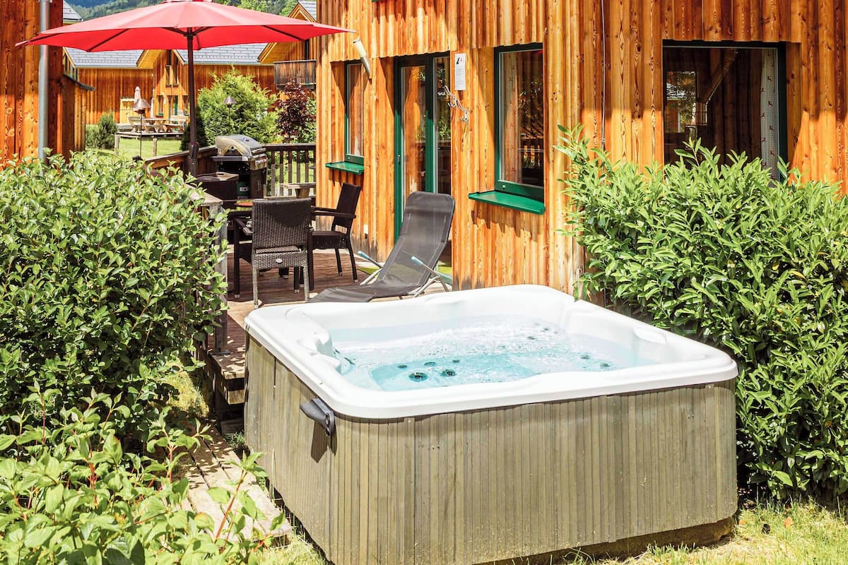 A wooden cabin with a hot tub, outdoor seating, and a mountain view.