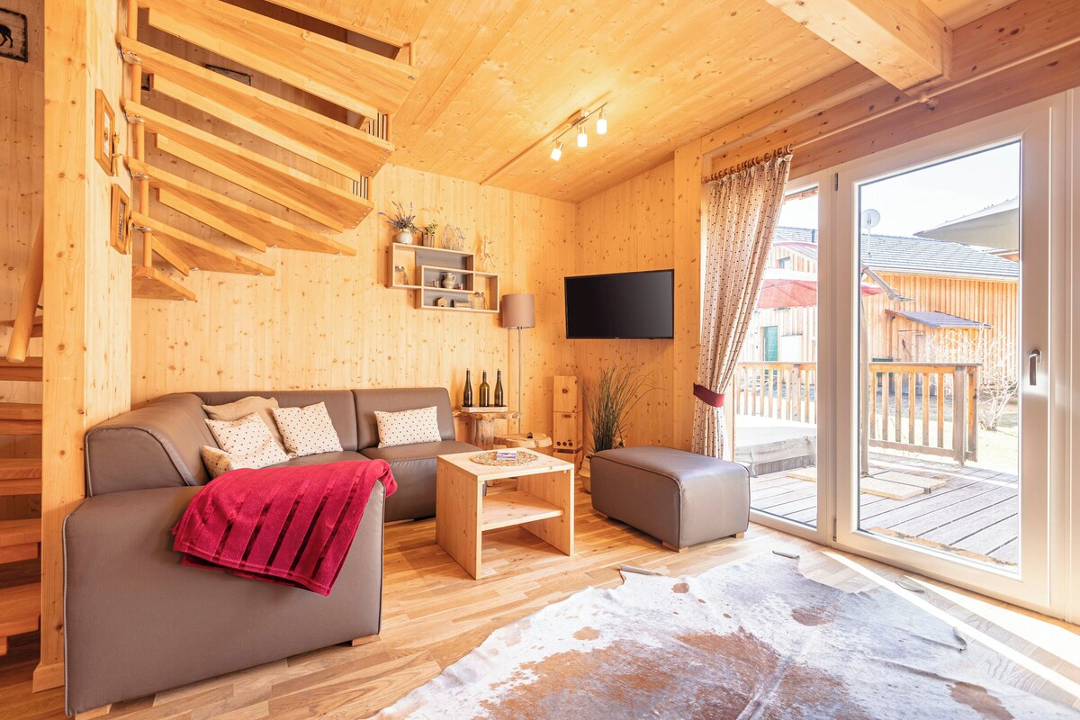 A wooden interior with a sofa, a coffee table, and a TV mounted on the wall.