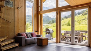 A modern interior with a sofa, coffee table, and wooden steps. - Kreischberg Chalets by ALPS RESORTS (Sankt Georgen am Kreischberg)