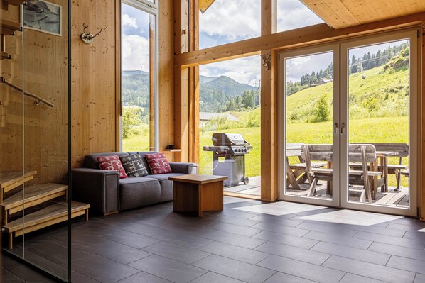 A modern interior with a sofa, coffee table, and wooden steps. - Kreischberg Chalets by ALPS RESORTS (Sankt Georgen am Kreischberg)